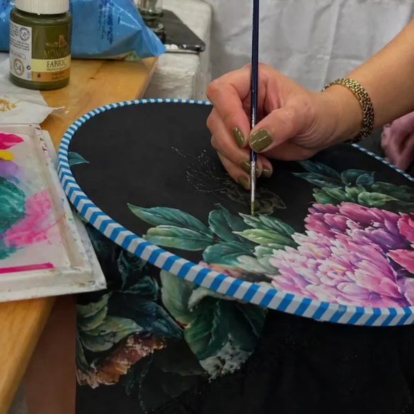 Artisan painting floral details on a custom luxury abaya