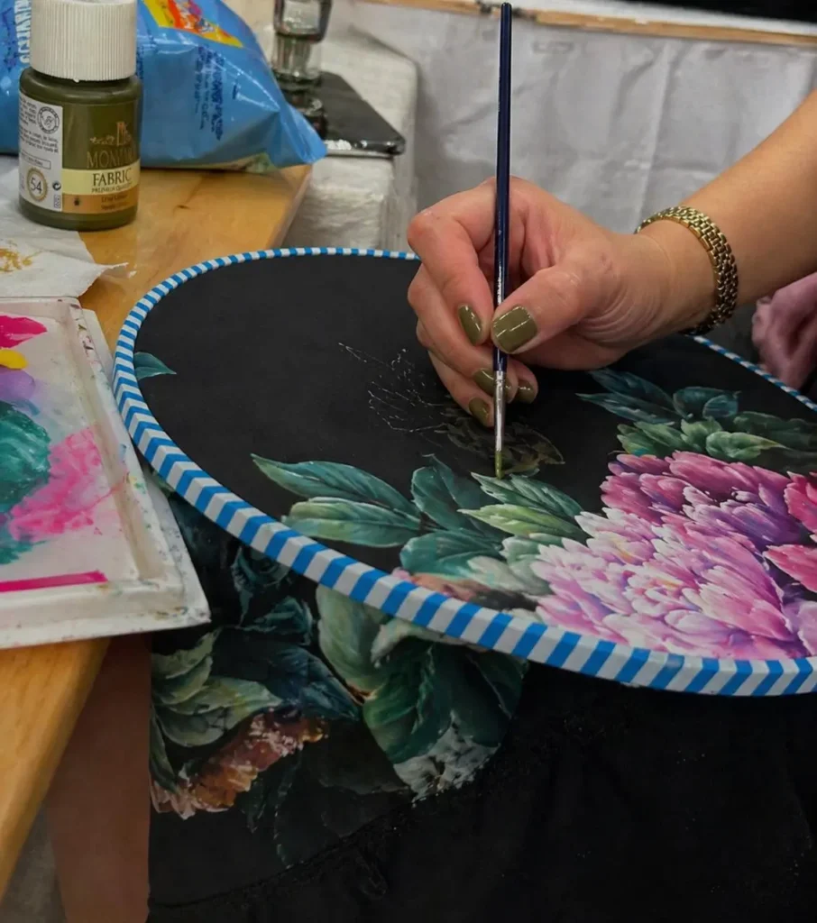 Artisan painting floral details on a custom luxury abaya