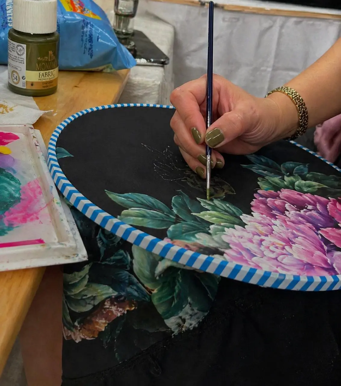 Artisan painting floral details on a custom luxury abaya